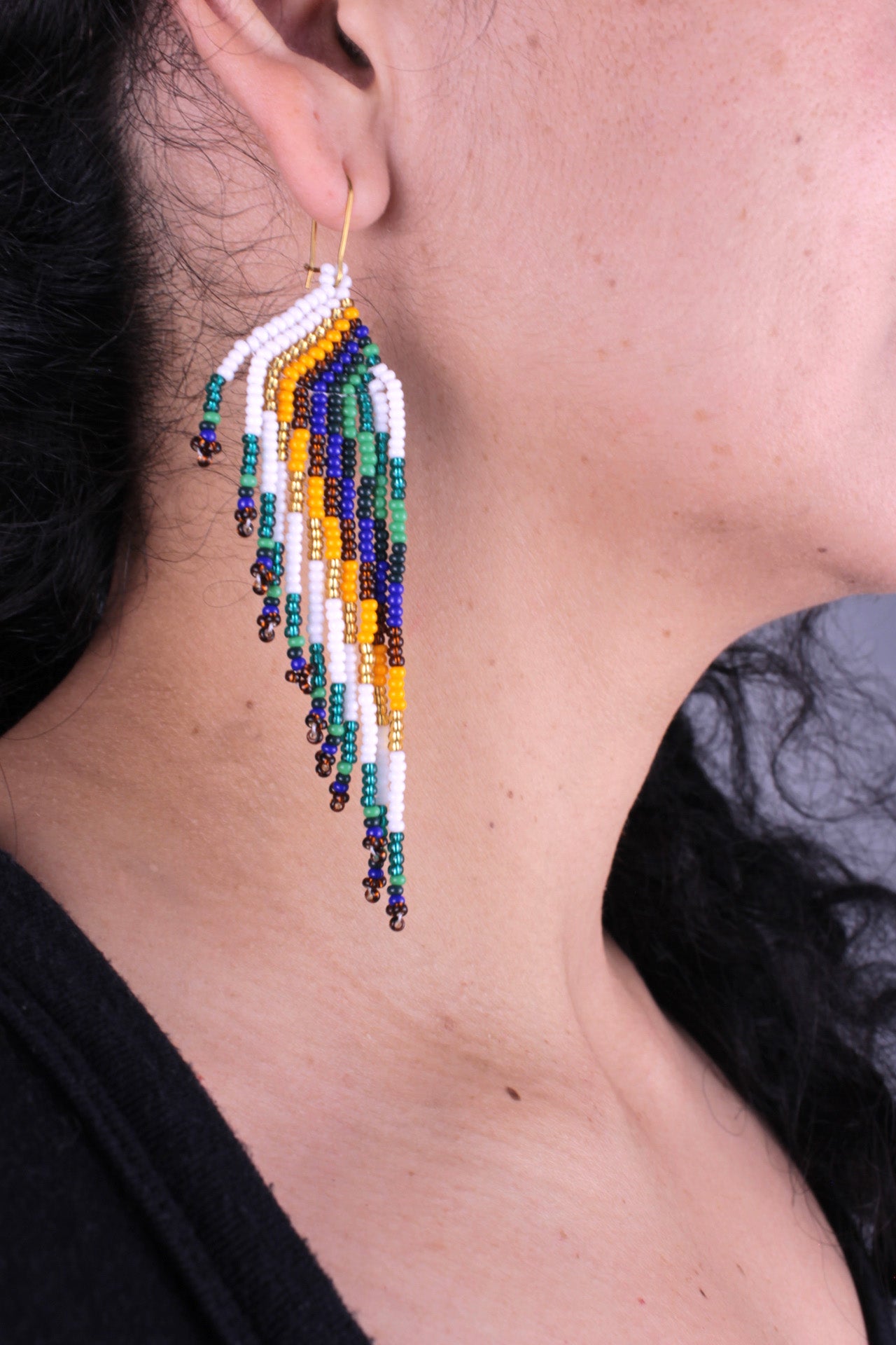 Boucles d’oreilles d’environ 9 cm x 3 cm, entièrement faites à la main en perles colorées (vert, blanc, doré, orange et bleu).