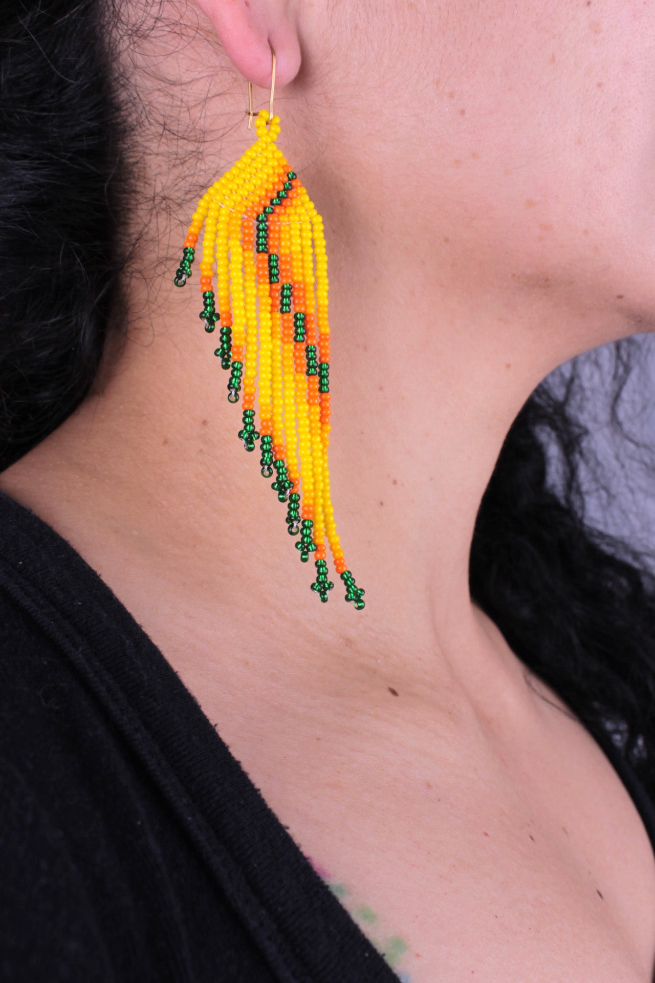Boucles d’oreilles d’environ 9 cm x 3 cm, entièrement faites à la main en perles colorées (vert, orange et jaune).